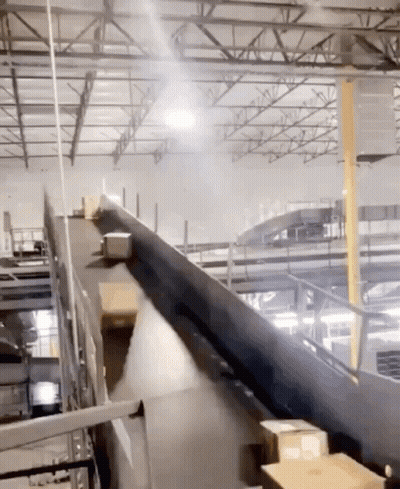 A Conveyor Belt With Boxes On It In A Large Warehouse GIF