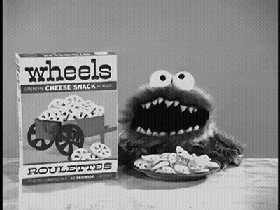A Cookie Monster Is Eating Wheels Roulettes From A Box . GIF