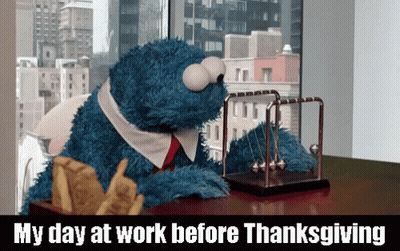 A Cookie Monster Is Sitting At A Desk With A Newton 'S Cradle On It GIF