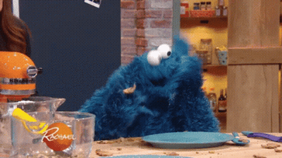 A Cookie Monster Is Sitting On A Kitchen Counter Next To A Measuring Cup That Says Rachael GIF