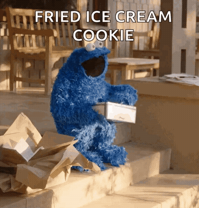 A Cookie Monster Is Sitting On A Set Of Steps Holding A Box Of Fried Ice Cream GIF