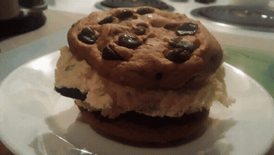 A Cookie With Chocolate Chips On Top Of A White Plate GIF