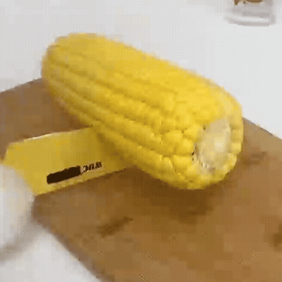 A Corn On The Cob Is Being Peeled On A Cutting Board . GIF