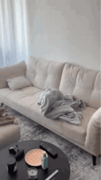 A Couch In A Living Room With A Blanket On It GIF