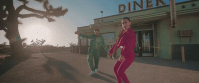 A Couple Dancing In Front Of A Diner That Has The Word Diner On It GIF