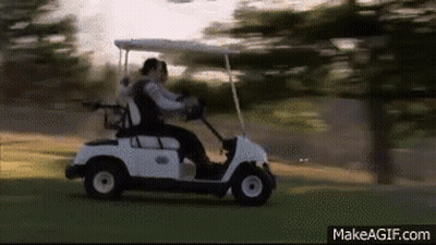A Couple Is Riding A Golf Cart On A Golf Course . GIF