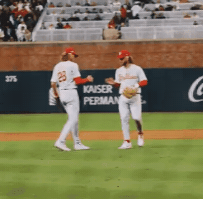 A Couple Of Baseball Players Are Standing On A Baseball Field Talking To Each Other . GIF