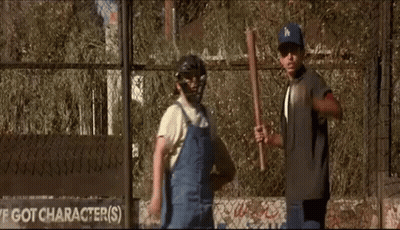 A Couple Of Boys Are Standing Next To Each Other In Front Of A Fence . GIF
