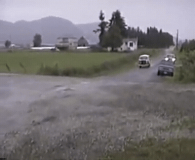 A Couple Of Cars Are Driving Down A Road In The Rain GIF