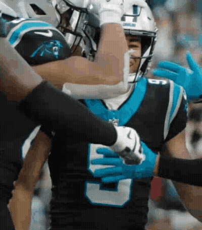 A Couple Of Football Players Are Hugging Each Other During A Game . GIF