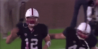 A Couple Of Football Players Are Standing On A Field . GIF