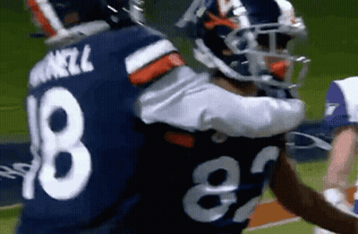 A Couple Of Football Players Hugging Each Other On The Field . GIF