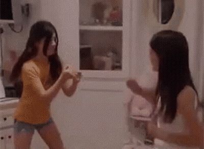 A Couple Of Girls Are Dancing In A Room . GIF