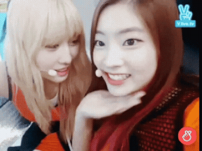 A Couple Of Girls Are Sitting Next To Each Other And Smiling For The Camera . GIF