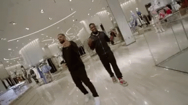 A Couple Of Men Are Dancing In A Store . GIF