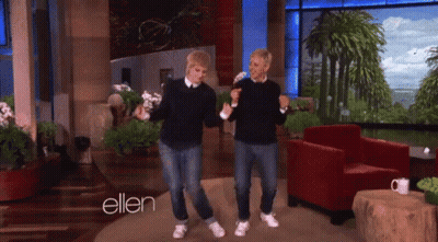 A Couple Of Men Are Dancing In Front Of A Sign That Says Ellen GIF