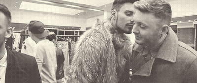 A Couple Of Men Are Kissing In A Room In A Black And White Photo . GIF