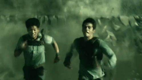 A Couple Of Men Are Running Through A Smokey Room . GIF
