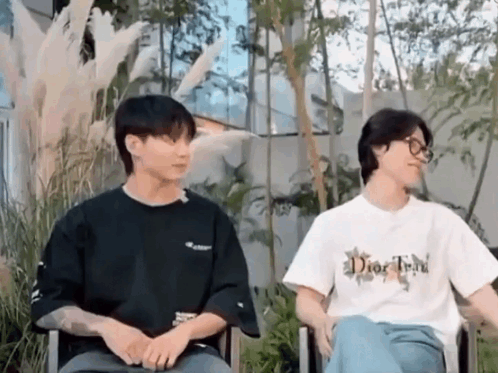 A Couple Of Men Are Sitting Next To Each Other In Chairs . GIF