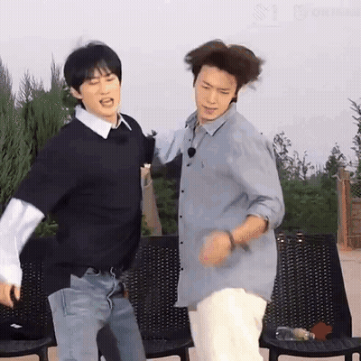 A Couple Of Men Are Standing Next To Each Other And Dancing . GIF