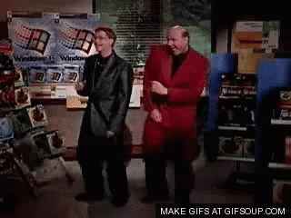 A Couple Of Men Are Standing Next To Each Other And One Is Wearing A Red Jacket . GIF