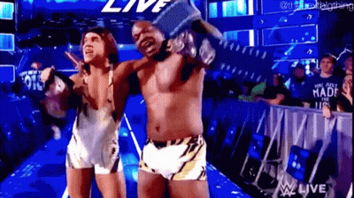A Couple Of Men Are Standing Next To Each Other In A Wrestling Ring Holding A Trophy . GIF