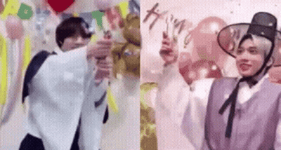 A Couple Of Men Are Standing Next To Each Other In Front Of Balloons And A Wall . GIF