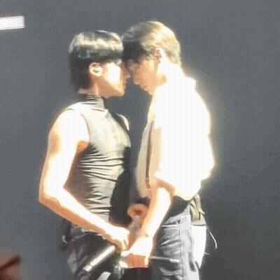 A Couple Of Men Are Standing Next To Each Other On A Stage . GIF
