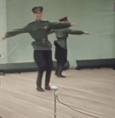 A Couple Of Men In Military Uniforms Are Dancing On A Stage . GIF