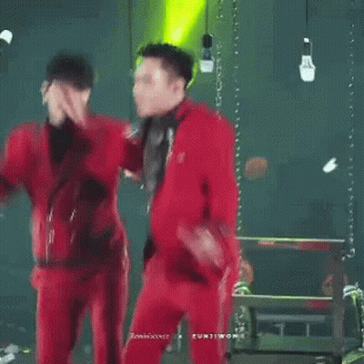 A Couple Of Men In Red Suits Are Dancing On A Stage GIF