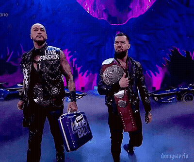 A Couple Of Men Standing Next To Each Other Holding A Briefcase And A Wrestling Belt . GIF