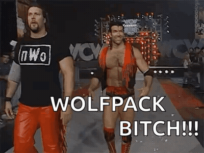A Couple Of Men Standing Next To Each Other On A Red Carpet With The Words `` Wolfpack Bitch '' Written On It . GIF