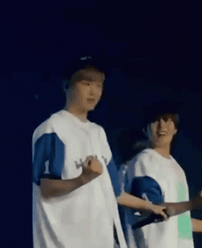 A Couple Of Men Standing Next To Each Other On A Stage . GIF