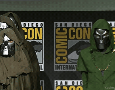 A Couple Of People Are Standing In Front Of A Comic Con Sign GIF