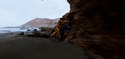 A Couple Of People Are Standing On A Rocky Beach GIF