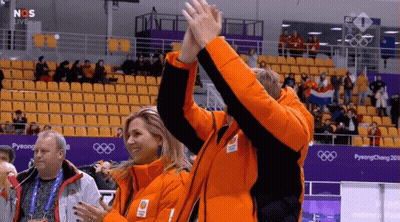A Couple Of People Giving Each Other A High Five In Front Of A Pyeongchang Sign GIF