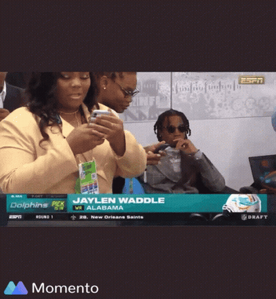 A Couple Of People Looking At Their Phones With The Name Jaylen Waddle On The Top GIF