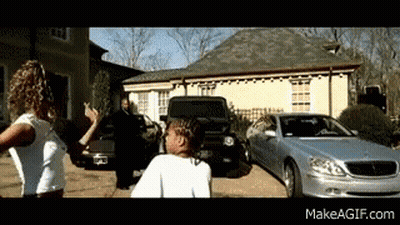 A Couple Of People Standing In Front Of A Silver Car And A House GIF