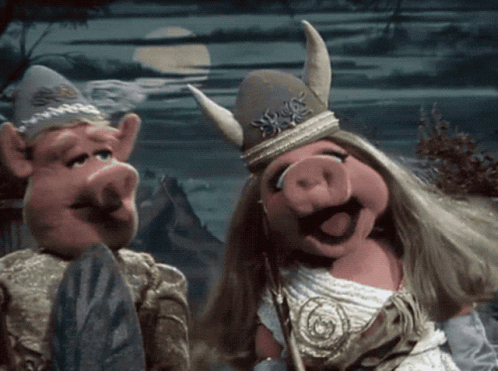 A Couple Of Pigs Standing Next To Each Other With One Wearing A Horned Hat GIF