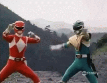 A Couple Of Power Rangers Are Standing Next To Each Other On A Rocky Hillside . GIF