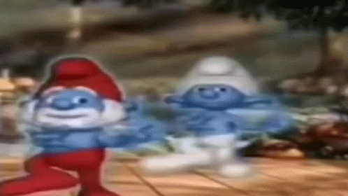 A Couple Of Smurfs Are Dancing On A Wooden Table . GIF