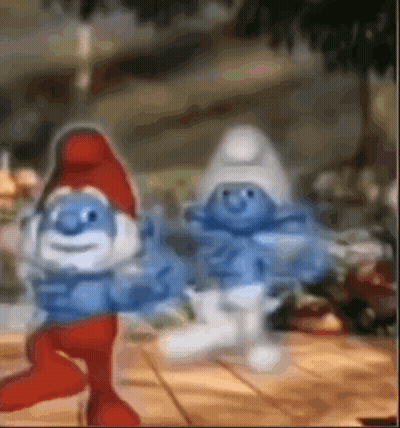 A Couple Of Smurfs Standing Next To Each Other On A Table . GIF