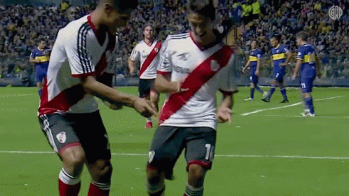 A Couple Of Soccer Players Are Dancing On The Field . GIF
