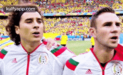A Couple Of Soccer Players Are Standing Next To Each Other On A Field . GIF