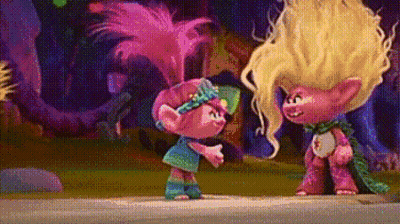 A Couple Of Trolls Standing Next To Each Other On A Sidewalk In A Forest . GIF