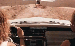 A Couple Of Women Are Driving A Car Down A Dirt Road . GIF
