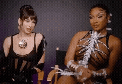 A Couple Of Women Are Sitting Next To Each Other In Chairs . GIF