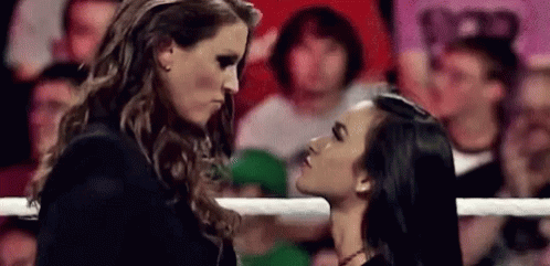 A Couple Of Women Are Standing Next To Each Other In A Ring And Kissing . GIF