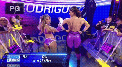 A Couple Of Women Are Standing Next To Each Other In Front Of A Crowd On A Wrestling Show . GIF