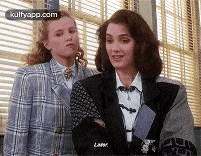 A Couple Of Women Are Standing Next To Each Other In Front Of A Window . GIF